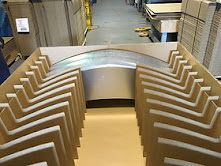 Curved sheet metal panels seated in corrugated nests on the plant floor