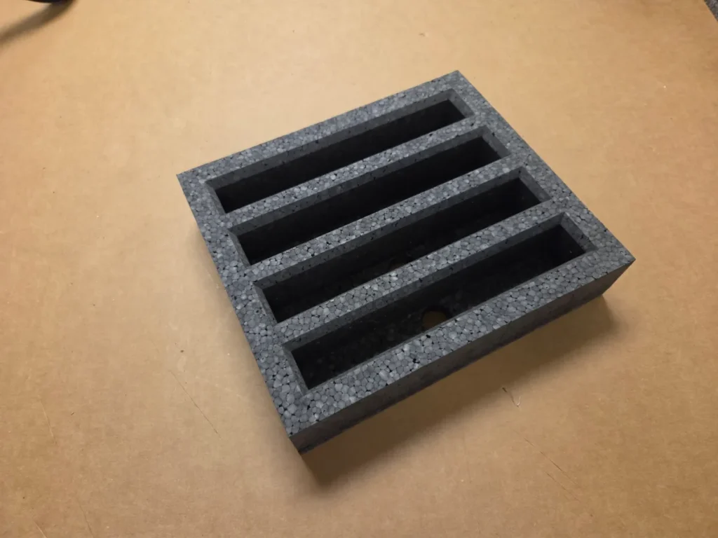 Black EPE foam insert with four long slots cut out to hold parts